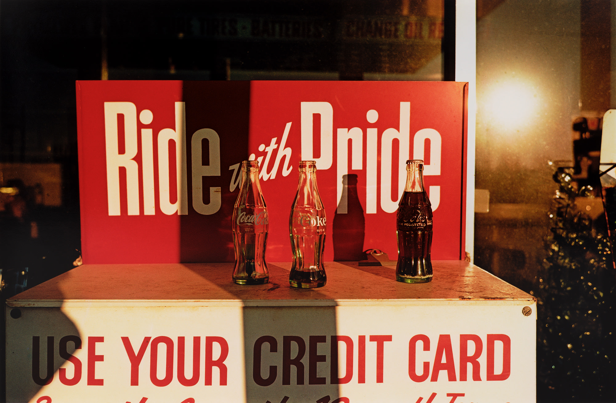 <p><strong>WILLIAM EGGLESTON</strong> <em>Untitled (Coke bottles Ride with Pride)</em>, circa 1970</p>
