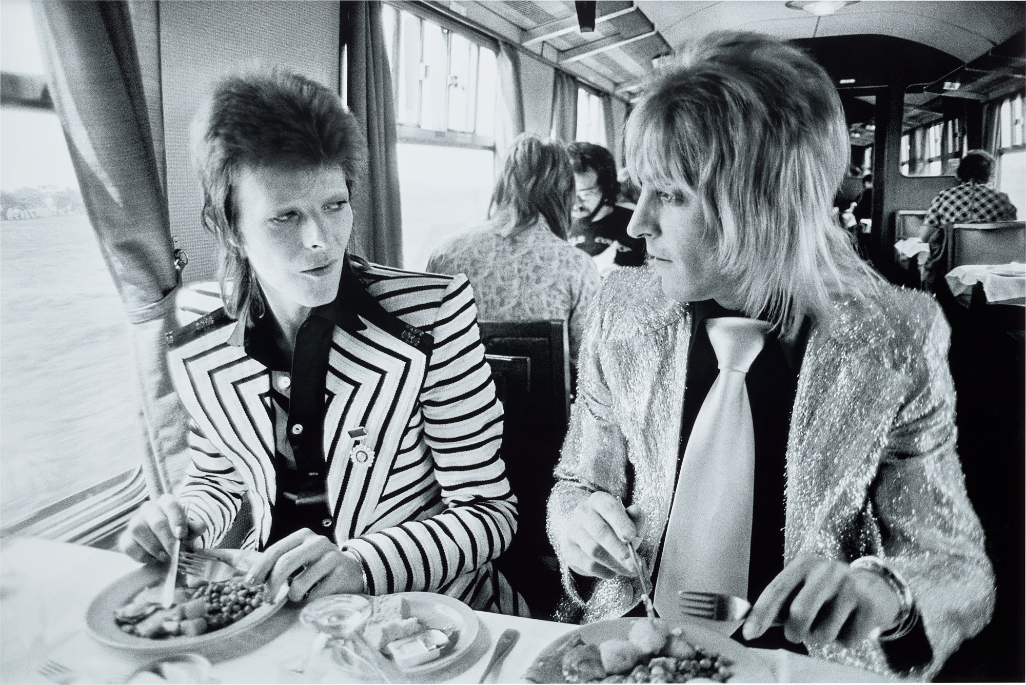 <p><strong>MICK ROCK </strong><em>David Bowie and Mick Ronson, Lunch on Train to Aberdeen</em>, 1973</p>

